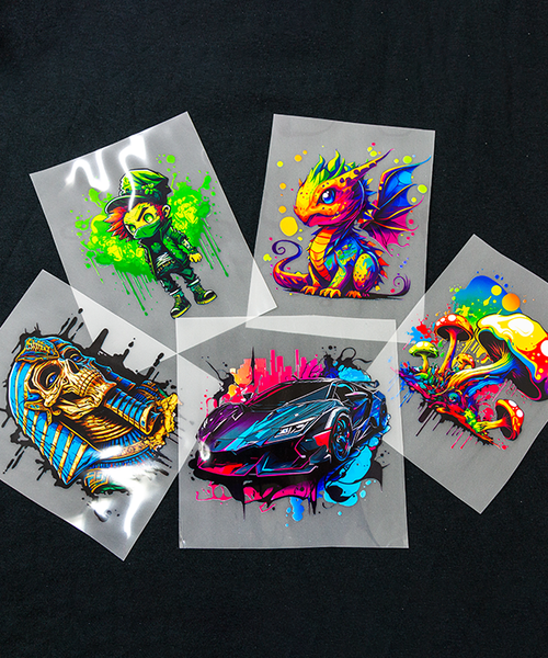 A collection of high-quality DTF transfer samples by Gravity Designs on a dark background. The vibrant, colorful designs include a cartoon dragon, a sports car, a stylized pharaoh, a graffiti-style character, and artistic mushrooms, showcasing vivid colors and sharp details.